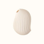 A compact, cream, ergonomic clitoral sucking device designed for pleasure, with a smooth surface and body safe silicone